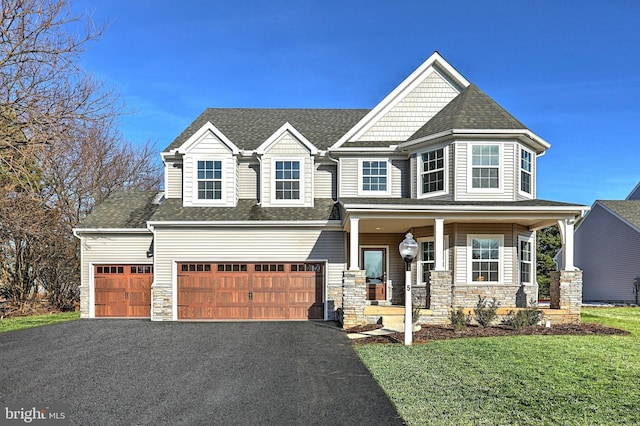 view of front facade featuring a garage, a front yard, and covered porch