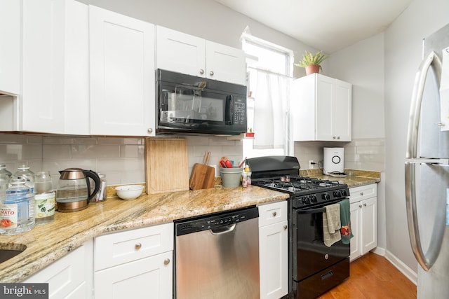 kitchen with tasteful backsplash, light hardwood / wood-style floors, white cabinets, and black appliances