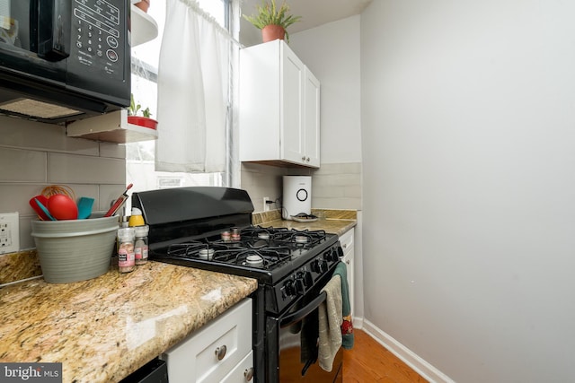 kitchen with light stone counters, white cabinets, light hardwood / wood-style flooring, black appliances, and backsplash