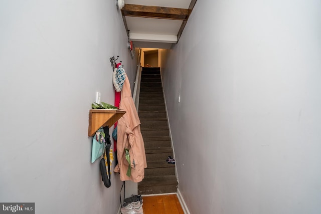 stairway featuring dark wood-type flooring and beamed ceiling