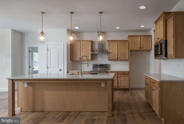 kitchen with a kitchen island with sink, stainless steel appliances, dark hardwood / wood-style floors, decorative light fixtures, and wall chimney exhaust hood