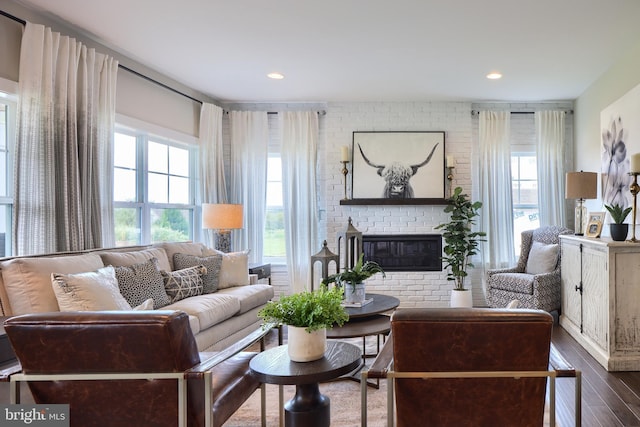 living room with a fireplace, wood-type flooring, and brick wall