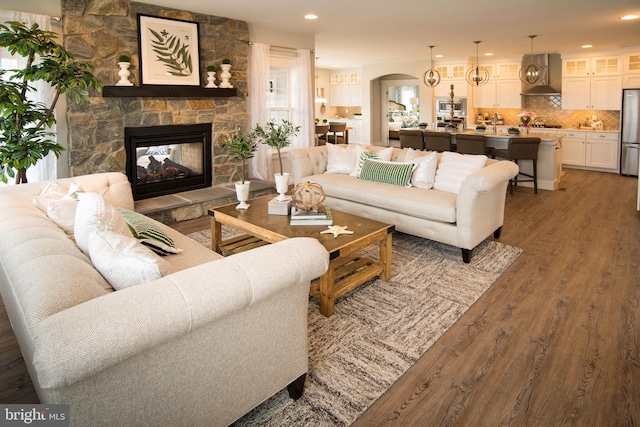 living room featuring dark wood-type flooring and a stone fireplace