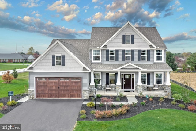 craftsman inspired home featuring covered porch, a garage, and a front lawn