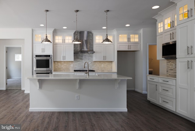 kitchen with an island with sink, white cabinets, and wall chimney exhaust hood