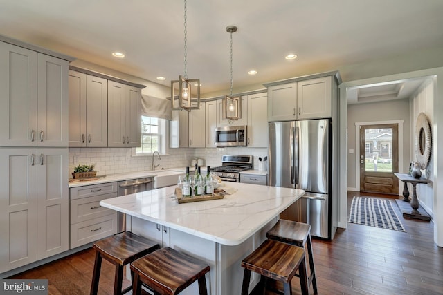 kitchen featuring dark hardwood / wood-style flooring, decorative backsplash, appliances with stainless steel finishes, and a center island