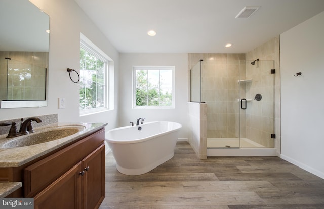 bathroom with wood-type flooring, vanity, and shower with separate bathtub