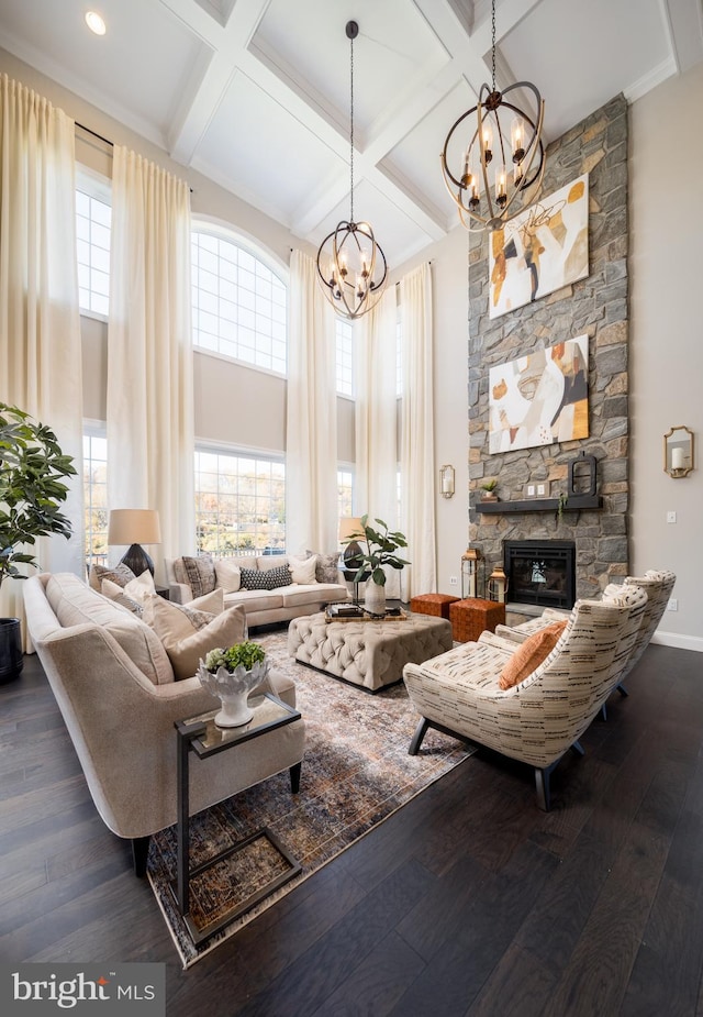 living room with an inviting chandelier, dark hardwood / wood-style flooring, coffered ceiling, a fireplace, and a towering ceiling