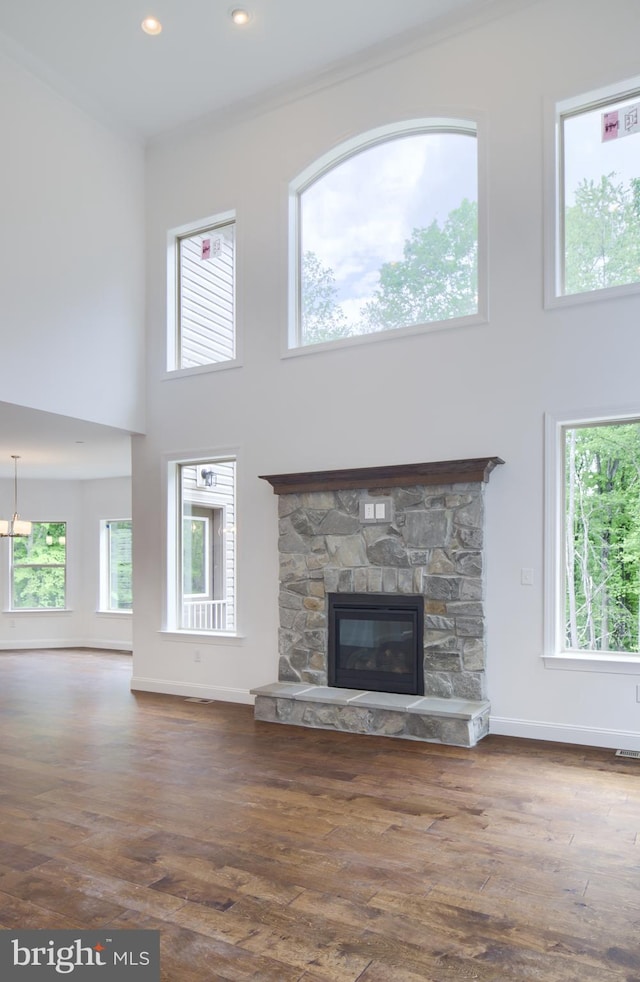 unfurnished living room featuring a stone fireplace, hardwood / wood-style floors, and a high ceiling