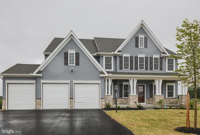 view of front of property featuring a porch, a garage, and a front lawn