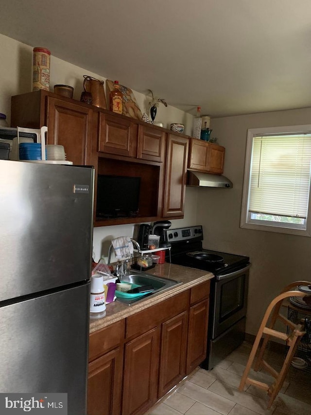 kitchen with light tile floors, range with electric cooktop, stainless steel refrigerator, and sink