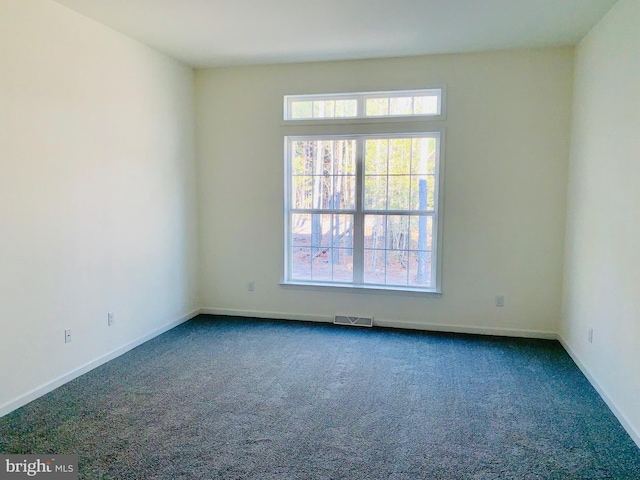 empty room with dark carpet and a wealth of natural light