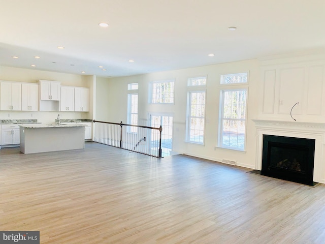 unfurnished living room with light wood-type flooring and sink