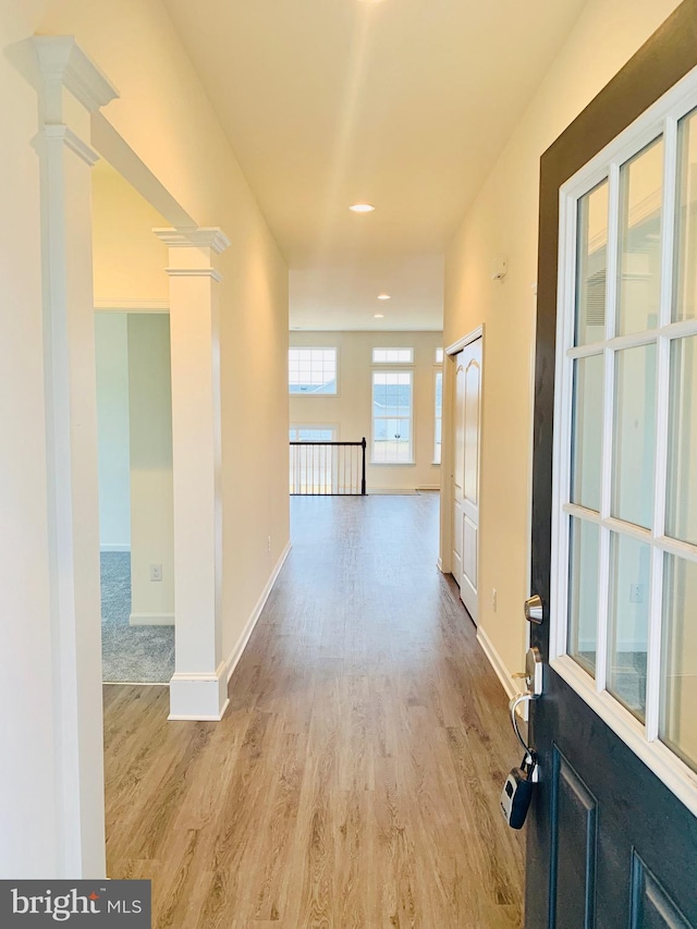 hallway with light hardwood / wood-style flooring and ornate columns