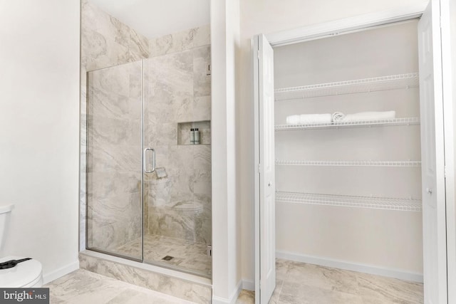 bathroom with a shower with door, toilet, and tile flooring