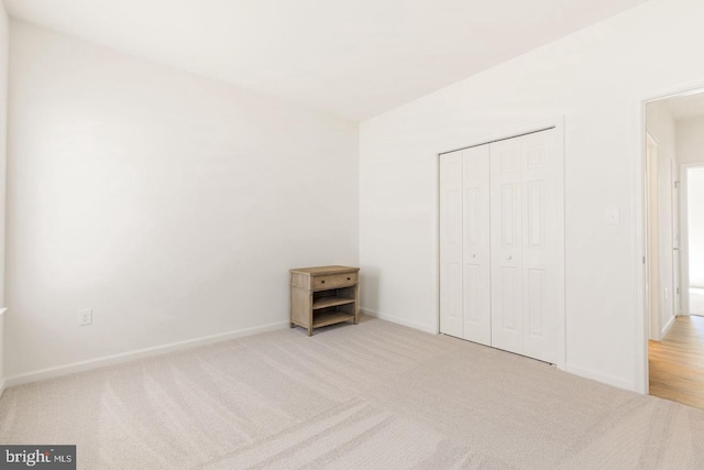 unfurnished bedroom with light colored carpet and a closet