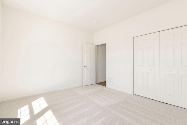 unfurnished bedroom featuring a closet and light carpet