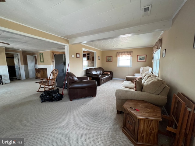 living room with beam ceiling, ornamental molding, and light colored carpet