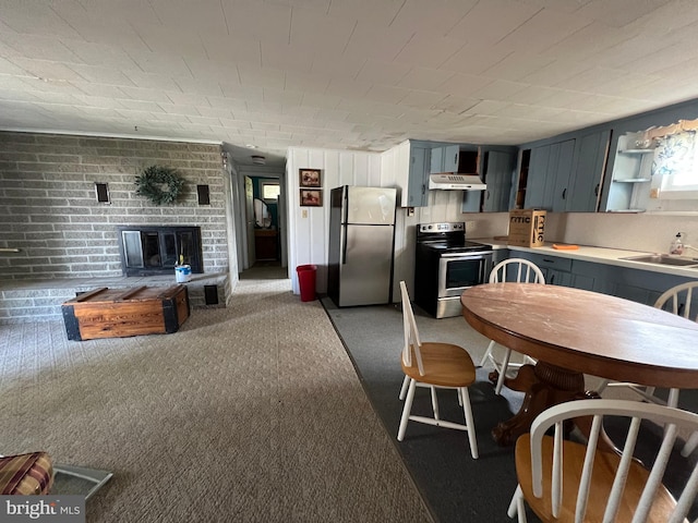 kitchen featuring brick wall, a brick fireplace, dark carpet, appliances with stainless steel finishes, and sink