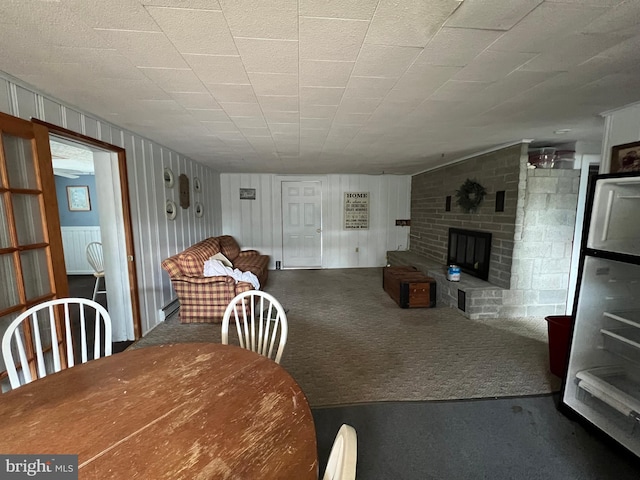 dining area with dark colored carpet, brick wall, and a brick fireplace