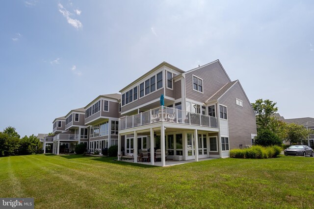 rear view of house featuring a balcony, a lawn, and a patio