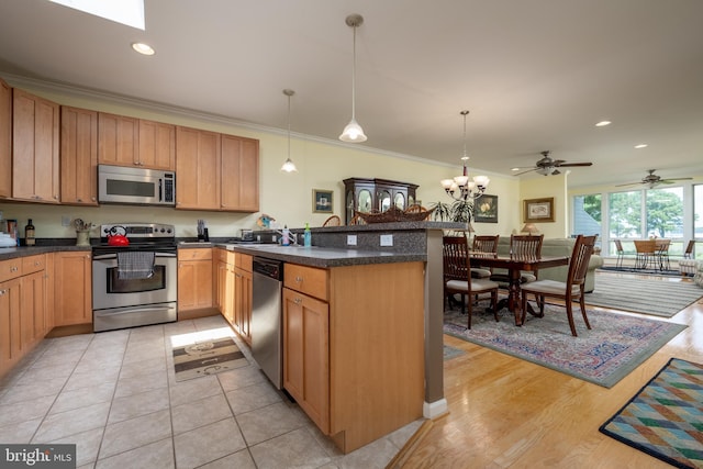 kitchen with light tile flooring, pendant lighting, stainless steel appliances, and ceiling fan with notable chandelier