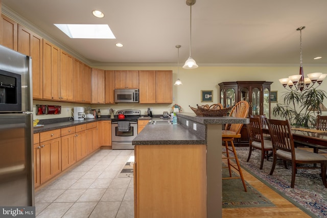 kitchen featuring pendant lighting, a notable chandelier, a skylight, a breakfast bar area, and appliances with stainless steel finishes