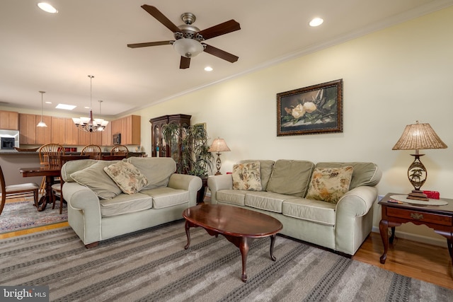 living room featuring ceiling fan with notable chandelier, ornamental molding, and hardwood / wood-style flooring