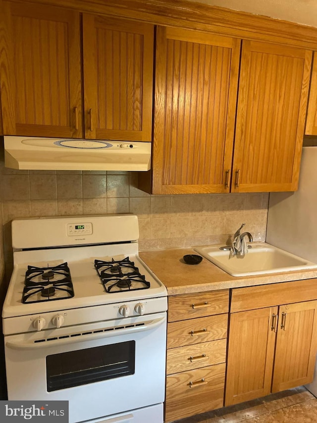 kitchen with sink, tasteful backsplash, and white gas stove