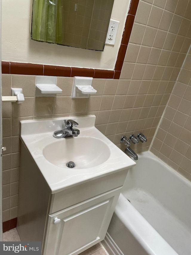 bathroom featuring tile walls, tiled shower / bath, backsplash, tile floors, and vanity