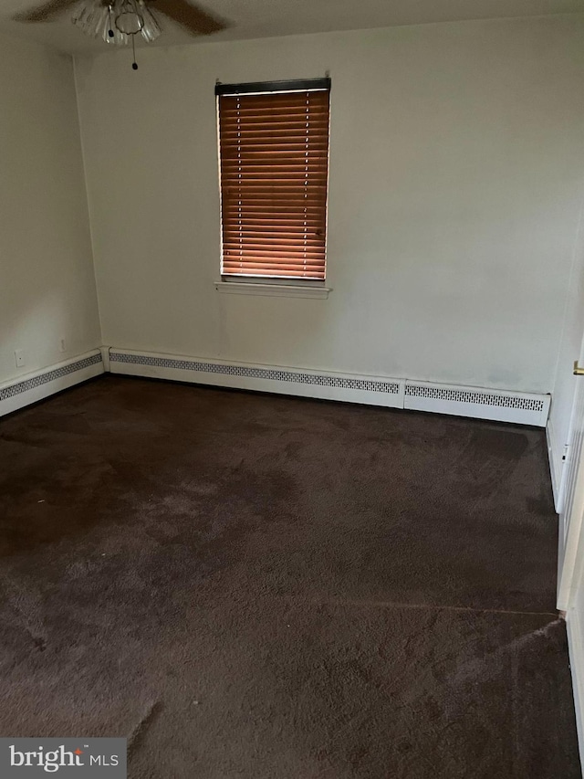 spare room with baseboard heating, dark carpet, and ceiling fan