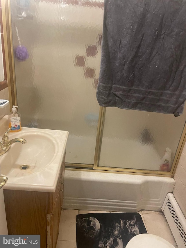 bathroom featuring combined bath / shower with glass door, a baseboard heating unit, vanity, and tile floors