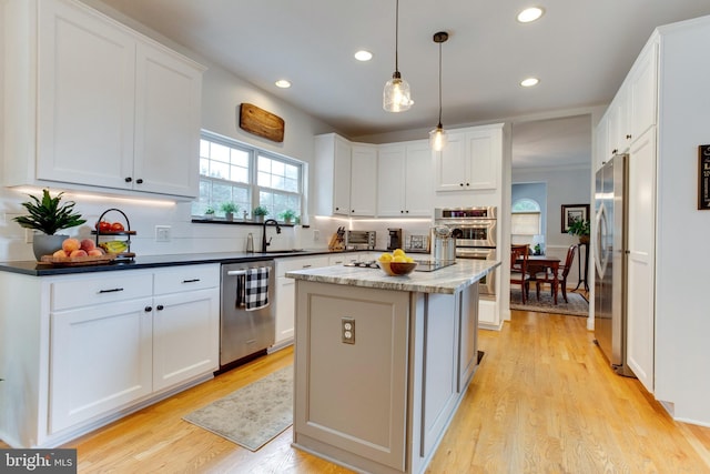 kitchen featuring a kitchen island, white cabinetry, appliances with stainless steel finishes, and light wood-type flooring