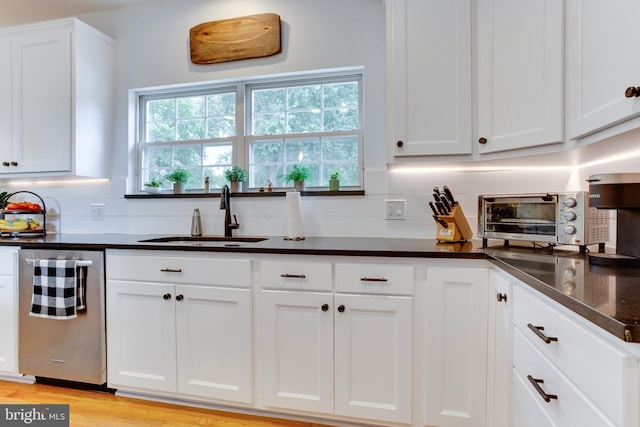 kitchen featuring backsplash, light hardwood / wood-style floors, dishwasher, sink, and white cabinetry