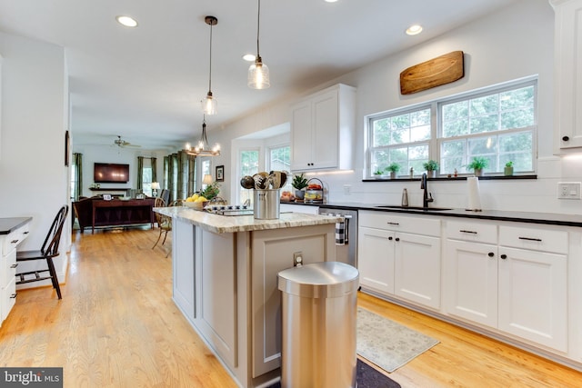 kitchen featuring hanging light fixtures, white cabinetry, sink, light hardwood / wood-style flooring, and tasteful backsplash