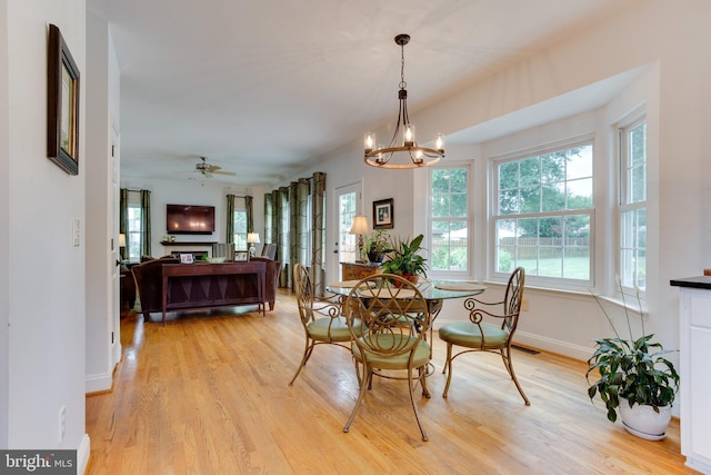 dining space with ceiling fan with notable chandelier and light wood-type flooring