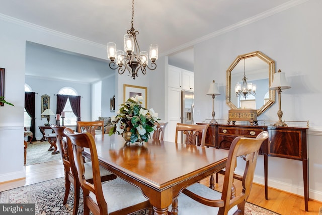 dining space featuring ornamental molding, light wood-type flooring, and an inviting chandelier