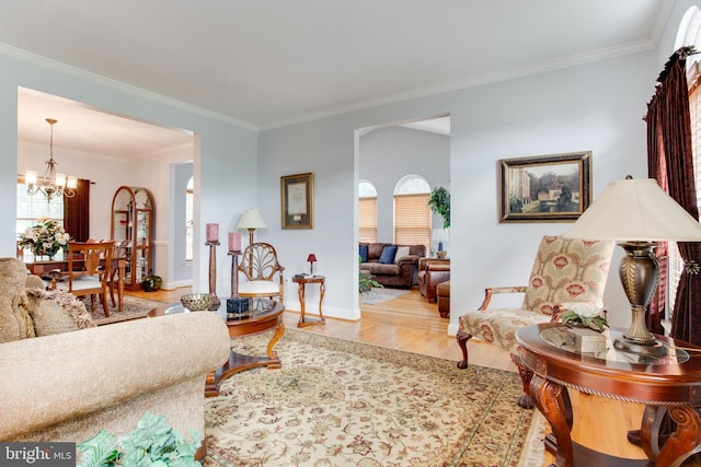 living room with crown molding, an inviting chandelier, and light hardwood / wood-style flooring