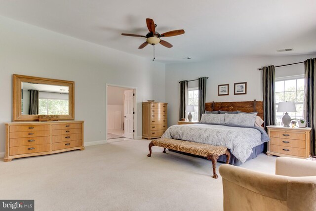 bedroom featuring ceiling fan, ensuite bathroom, and light colored carpet