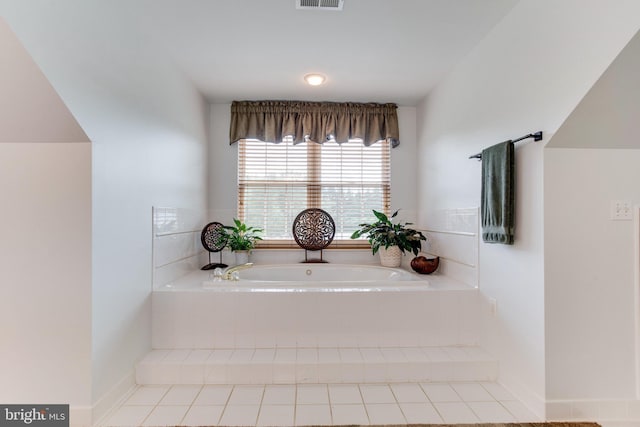 bathroom with a relaxing tiled bath and tile flooring