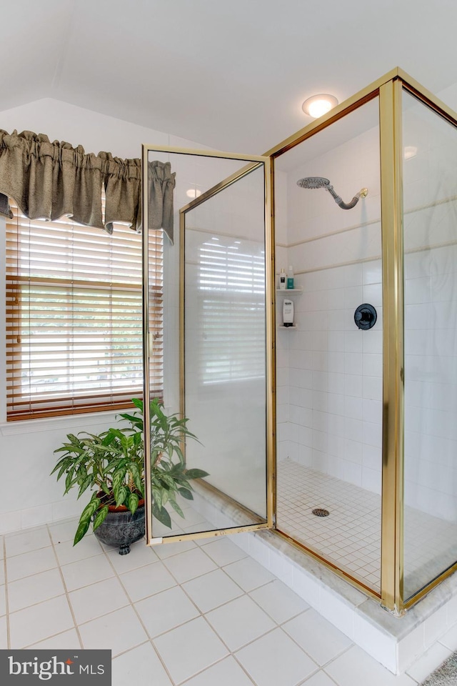 bathroom with lofted ceiling, a shower with door, and tile floors