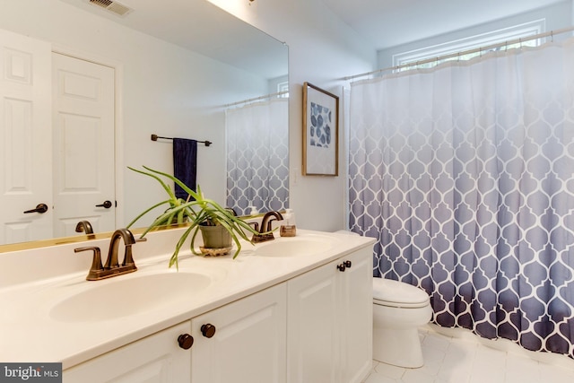 bathroom with double sink vanity, toilet, and tile floors