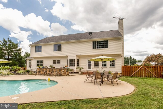 rear view of house with a lawn, a fenced in pool, and a patio area