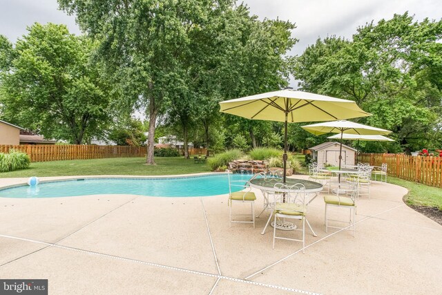 view of pool featuring a storage unit, a yard, and a patio