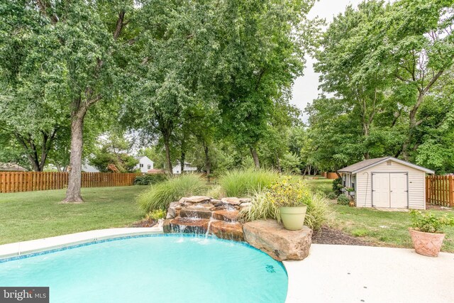 view of swimming pool featuring a patio, a yard, pool water feature, and a shed