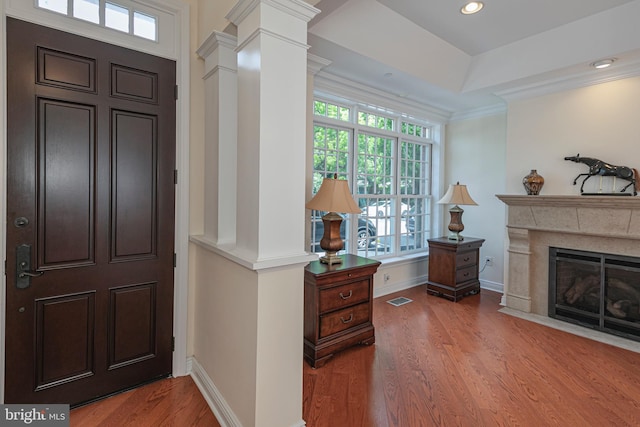 foyer with a high end fireplace, wood-type flooring, and crown molding