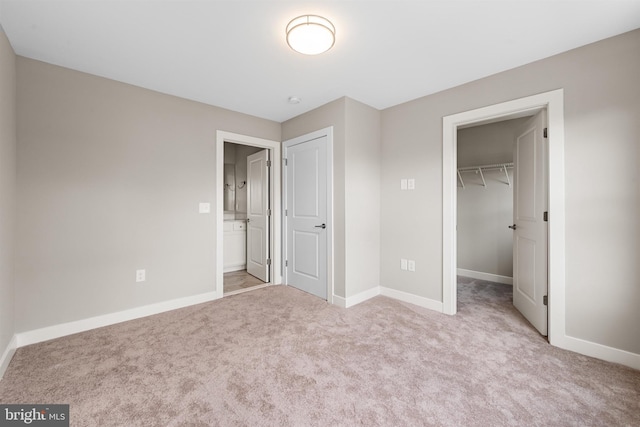 unfurnished bedroom featuring a closet, light carpet, and a spacious closet