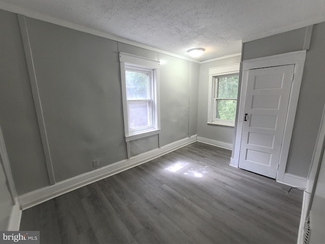 spare room featuring a textured ceiling and dark hardwood / wood-style flooring