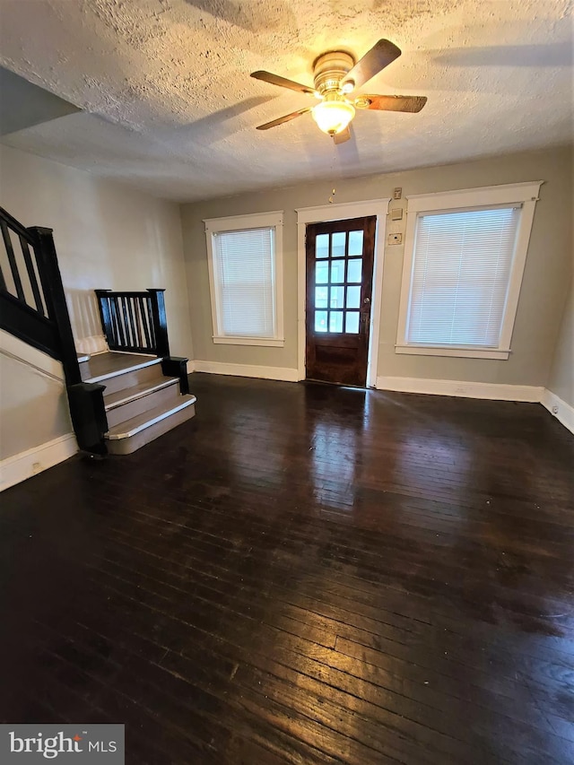 entryway featuring ceiling fan, dark wood-type flooring, and a textured ceiling