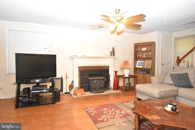 living room featuring ceiling fan, a fireplace, and light hardwood / wood-style floors